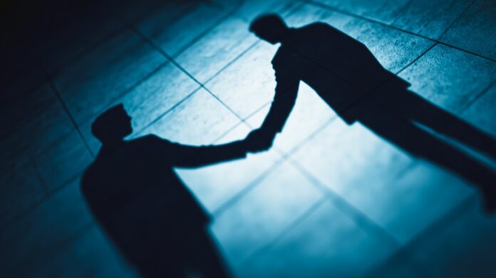 Shadowy Business Handshake on Blue Floor, Corporate Deal Concept Rund 25% der mittelständischen Unternehmen der Senior-Generation ziehen in Betracht ihr Unternehmen aufzugeben.